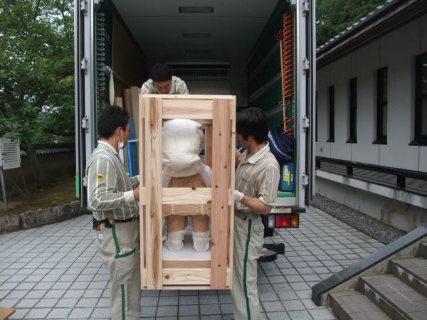 木枠に入った埴輪を2人の配達員が慎重に車に積んでいる写真