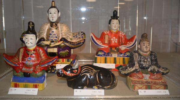 黒い牛の人形が1点と天神様の人形が4点展示されている写真