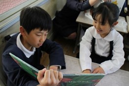 男の子が本を広げ女の子と一緒に見ている写真