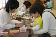 子どもとお母さんが一緒にクレヨンを使って絵を描いている写真