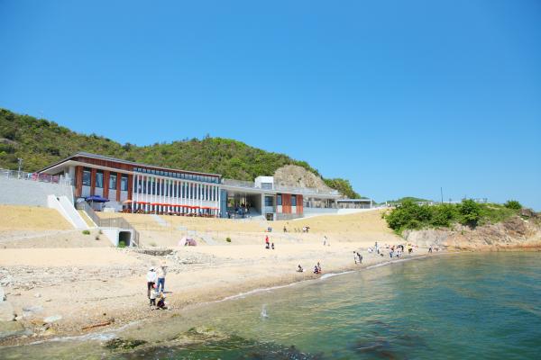 青い海と砂浜の奥に建っている道の駅みつの外観写真
