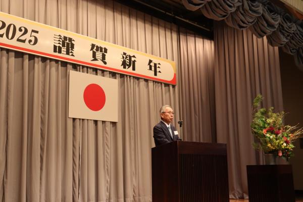 壇上の演台の上に置かれているマイクの前に立ち、話をしている市長の写真