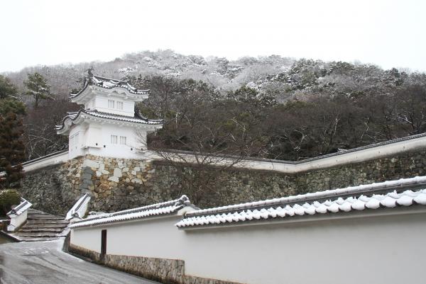 白亜の城壁沿いの階段を上がった先にある、白壁の龍野城と積もった雪の白さが同化している写真